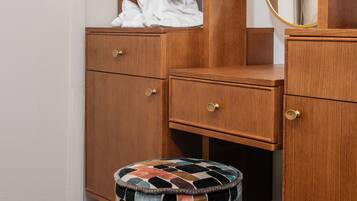 Une coiffeuse en bois avec un miroir, un peignoir et un tapis à motifs.