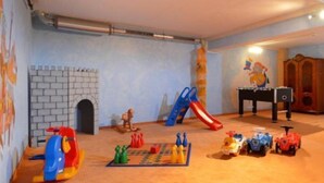 A playroom with a castle mural, a slide, a foosball table, and various toys. - Holiday (Ellmau)