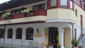 A corner building with a balcony, a sign reading "Hotel Restaurant," and a staircase leading to an upper floor. - Holiday (Ellmau)