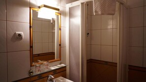 Un baño con espejo, lavamanos y ducha.