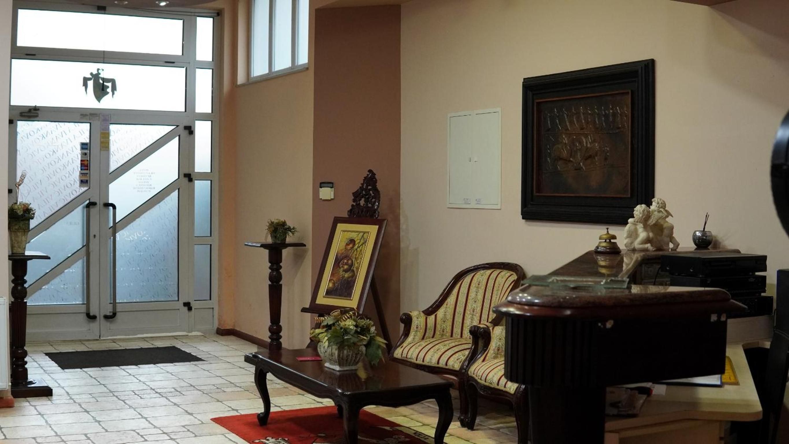 Zona de recepción con escalera, un cuadro enmarcado, una silla, una mesa y una estatua.