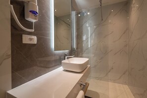 Ein modernes Badezimmer mit einem weißen Waschbecken, einer Duschbrause und einer gläsernen Duschkabine.