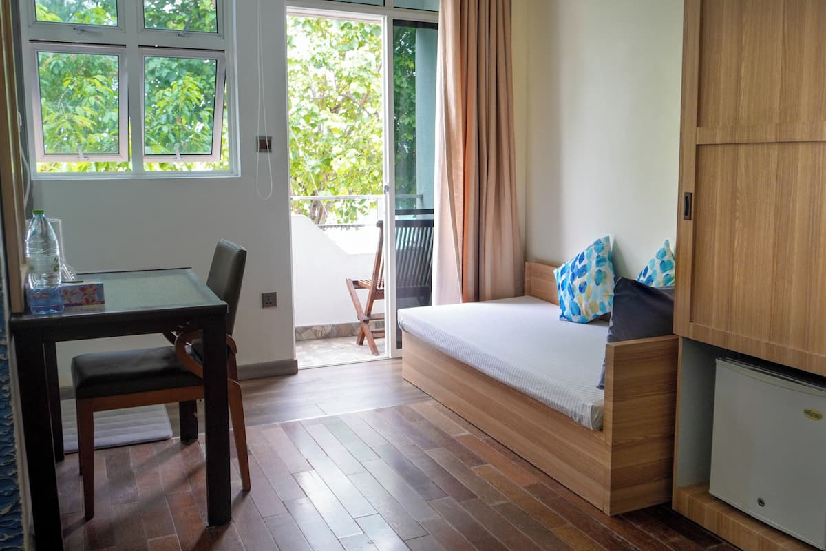 A compact room with a bed, a small table, and a cabinet.