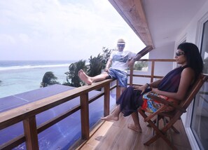 A balcony with a wooden railing overlooking a beach and ocean. - Ripple Beach Inn (Hulhumalé)