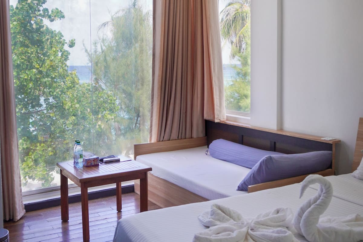 A hotel room with a large bed, a wooden table, and a view of the outdoors.