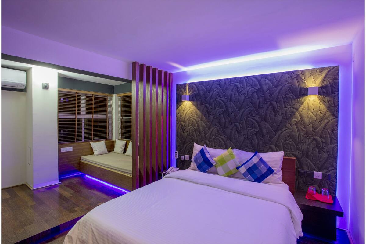 A modern bedroom with a large bed, a built-in bench, and a decorative wall panel.