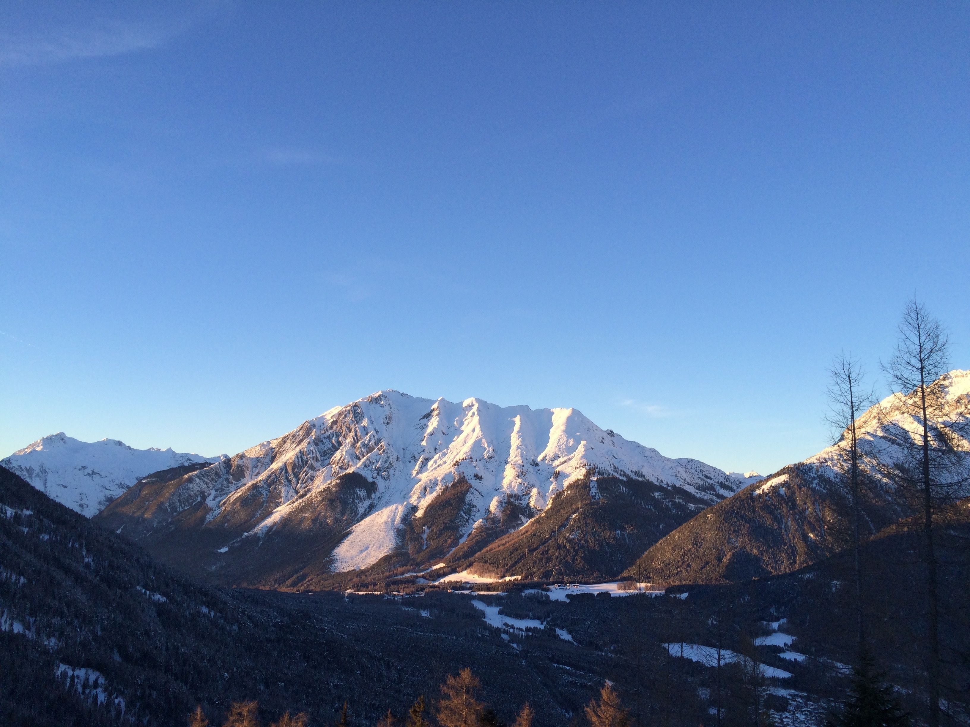 A mountain landscape with snow-covered peaks and a valley.
