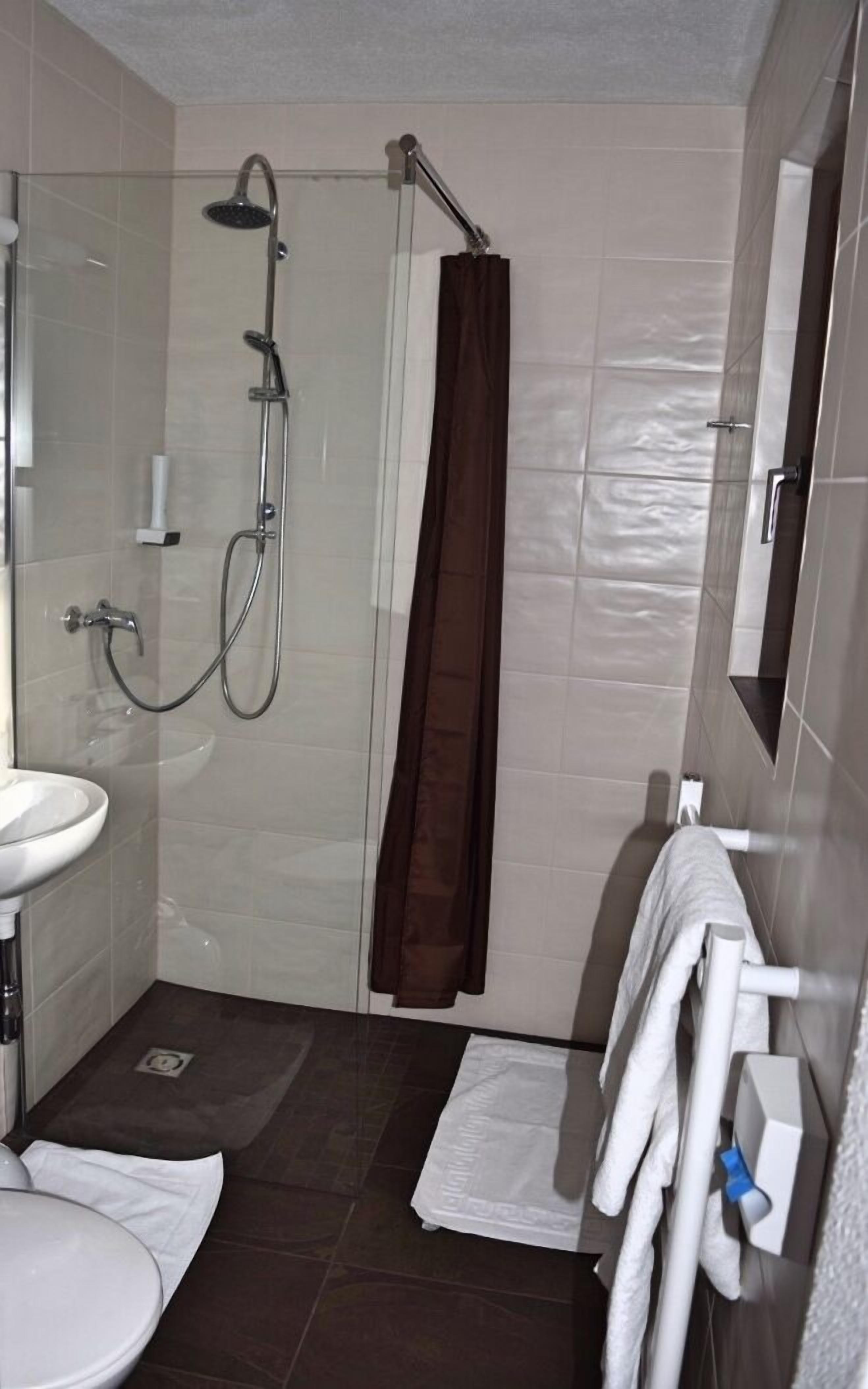 A bathroom with a glass-enclosed shower, a white sink, and a towel rack.