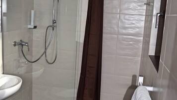 A bathroom with a glass-enclosed shower, a white sink, and a towel rack.