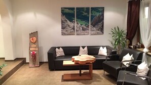 Een moderne woonkamer met een zwarte bank, een houten salontafel en een groot schilderij erboven.