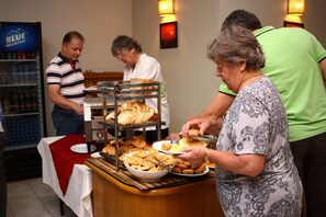 A buffet setup with various food items and a beverage cooler. - Arthawka Hotel (Nyaung-U)