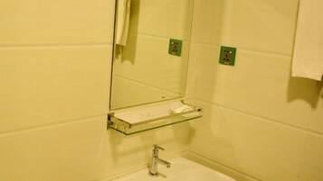 Un baño con un lavamanos blanco, un espejo y un perchero para toallas.