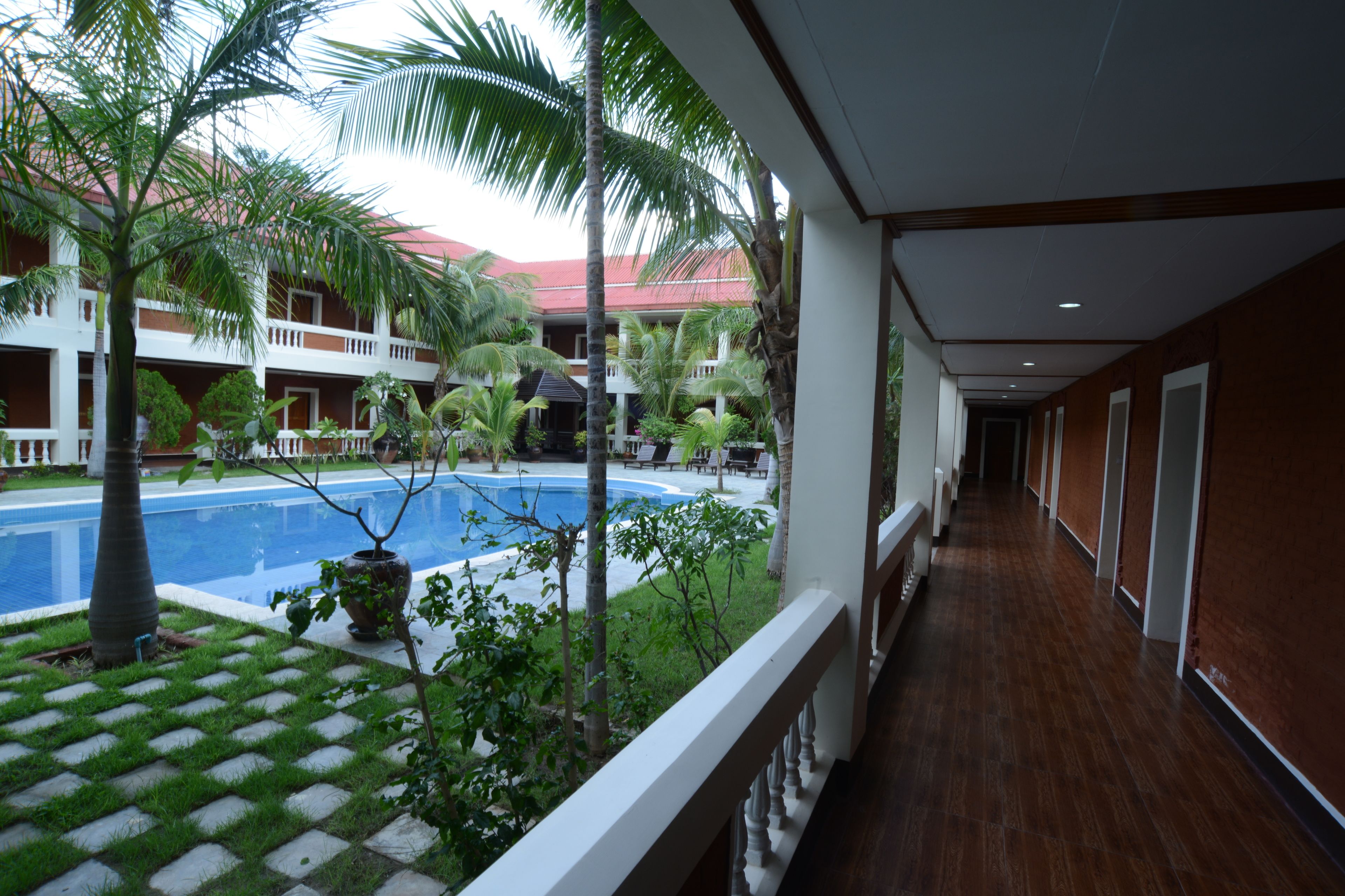 A hotel corridor with a pool area visible through the glass railing.