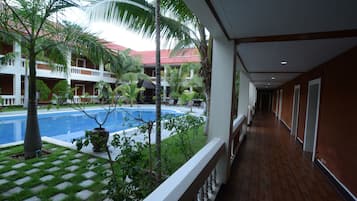 A hotel corridor with a pool area visible through the glass railing.