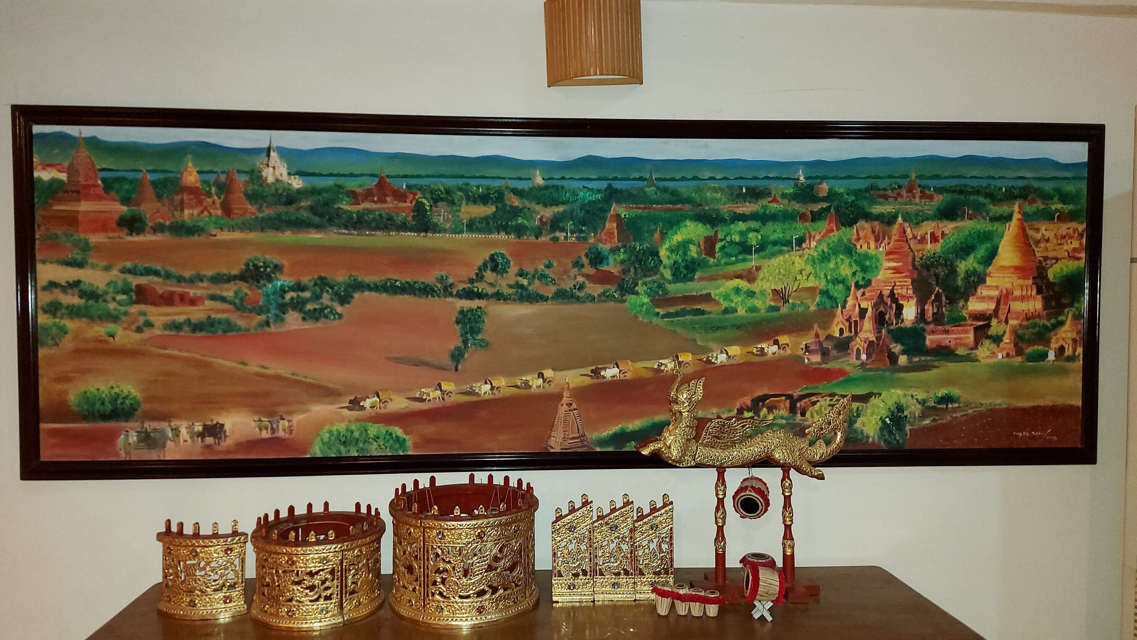 Una pintura de un paisaje con templos y un carro dorado.
