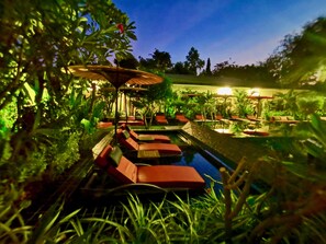 Una piscina al aire libre, sombrillas, sillones reclinables de piscina