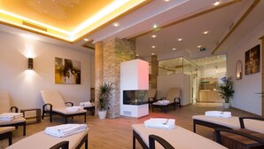 A modern spa area with lounge chairs, a stone pillar, and a glass partition. - Hotel Obermair (Fieberbrunn)