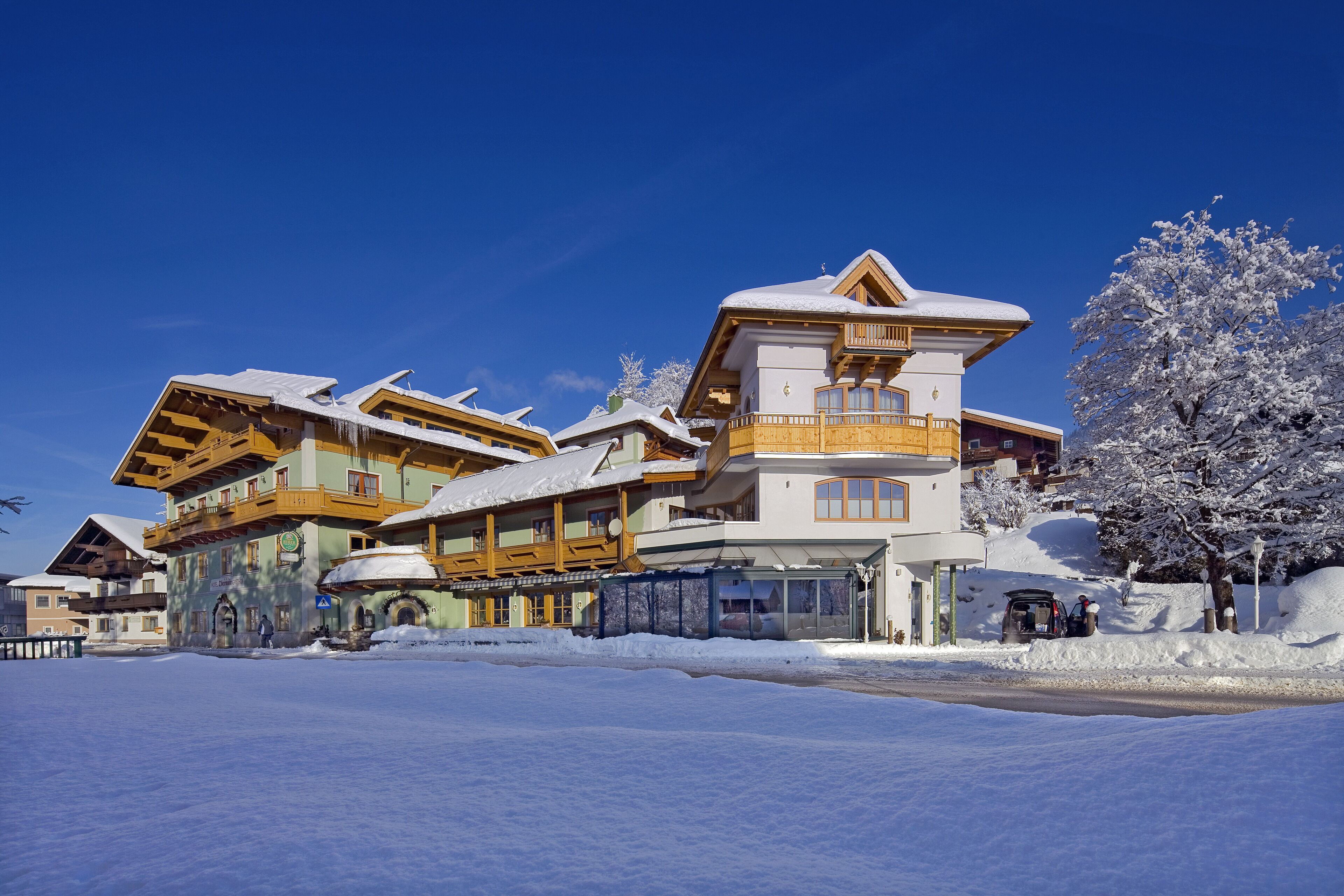 Ein mehrstöckiges Hotel mit verschneietem Dach und hölzernen Balkonen, umgeben von Schnee.