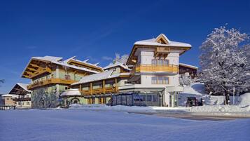 Un hôtel à plusieurs étages, dont le toit est recouvert de neige et qui possède des balcons en bois, le tout entouré de neige.