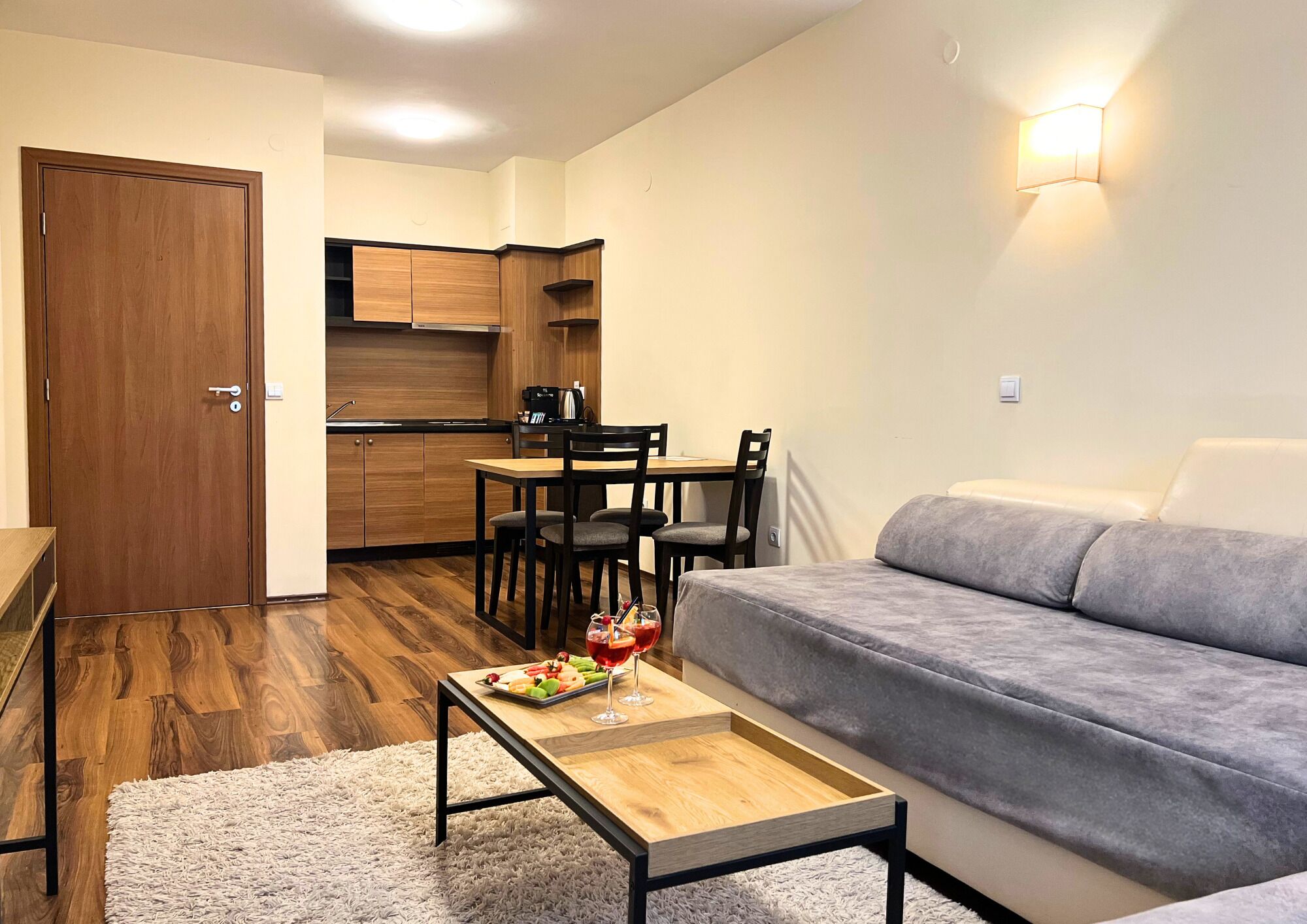 Un espacio habitable compacto con kitchenette, zona de comedor y sofá.