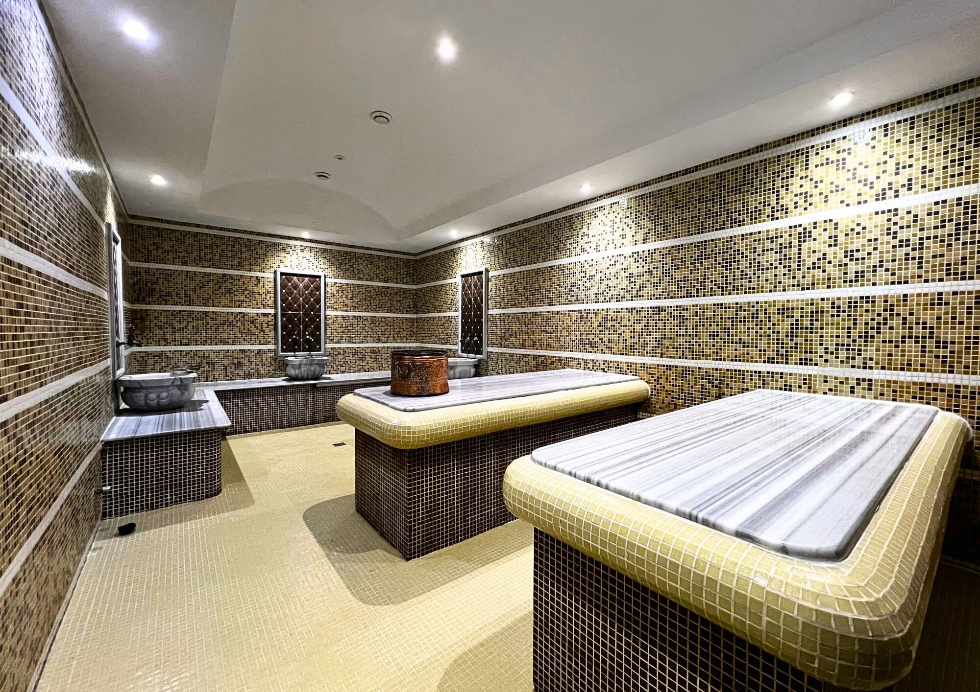A bathroom with a tiled mosaic wall, a sink with a basin, a bathtub, and a shower area.
