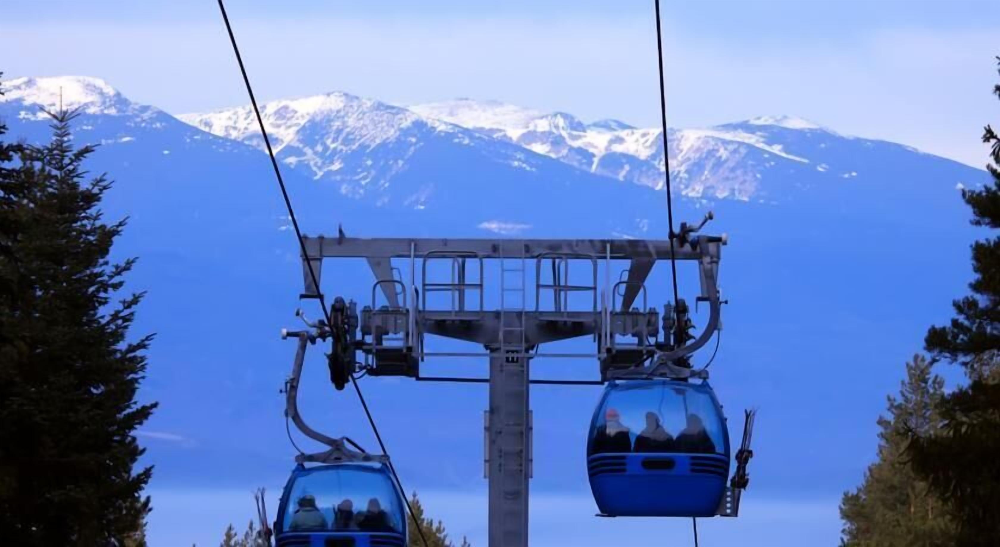 A cable car system with passengers, set against a backdrop of snow-capped mountains.