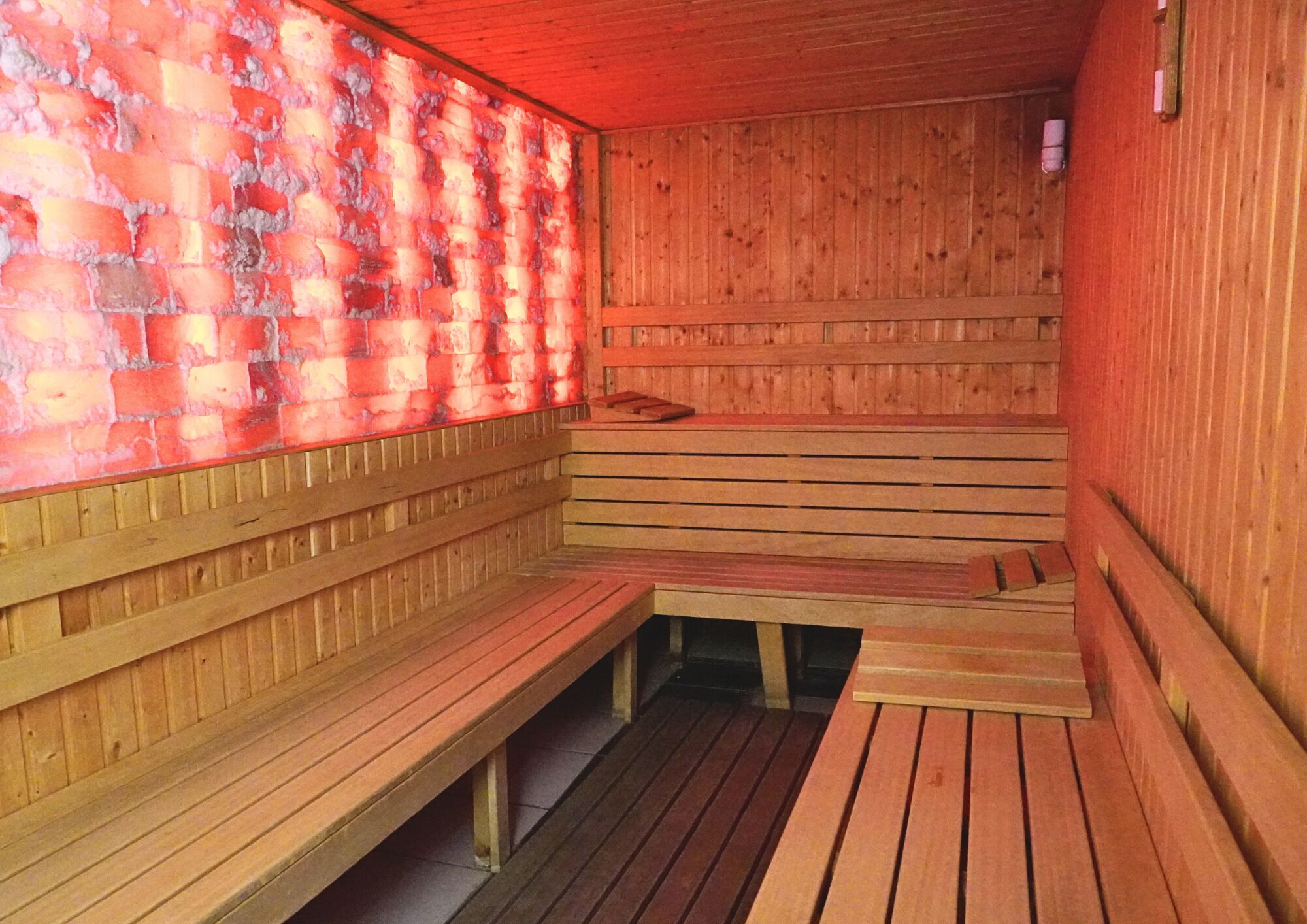 A sauna with wooden benches and a brick wall.