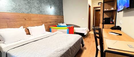 A hotel room with a bed, a desk, a chair, a television, and a wardrobe.