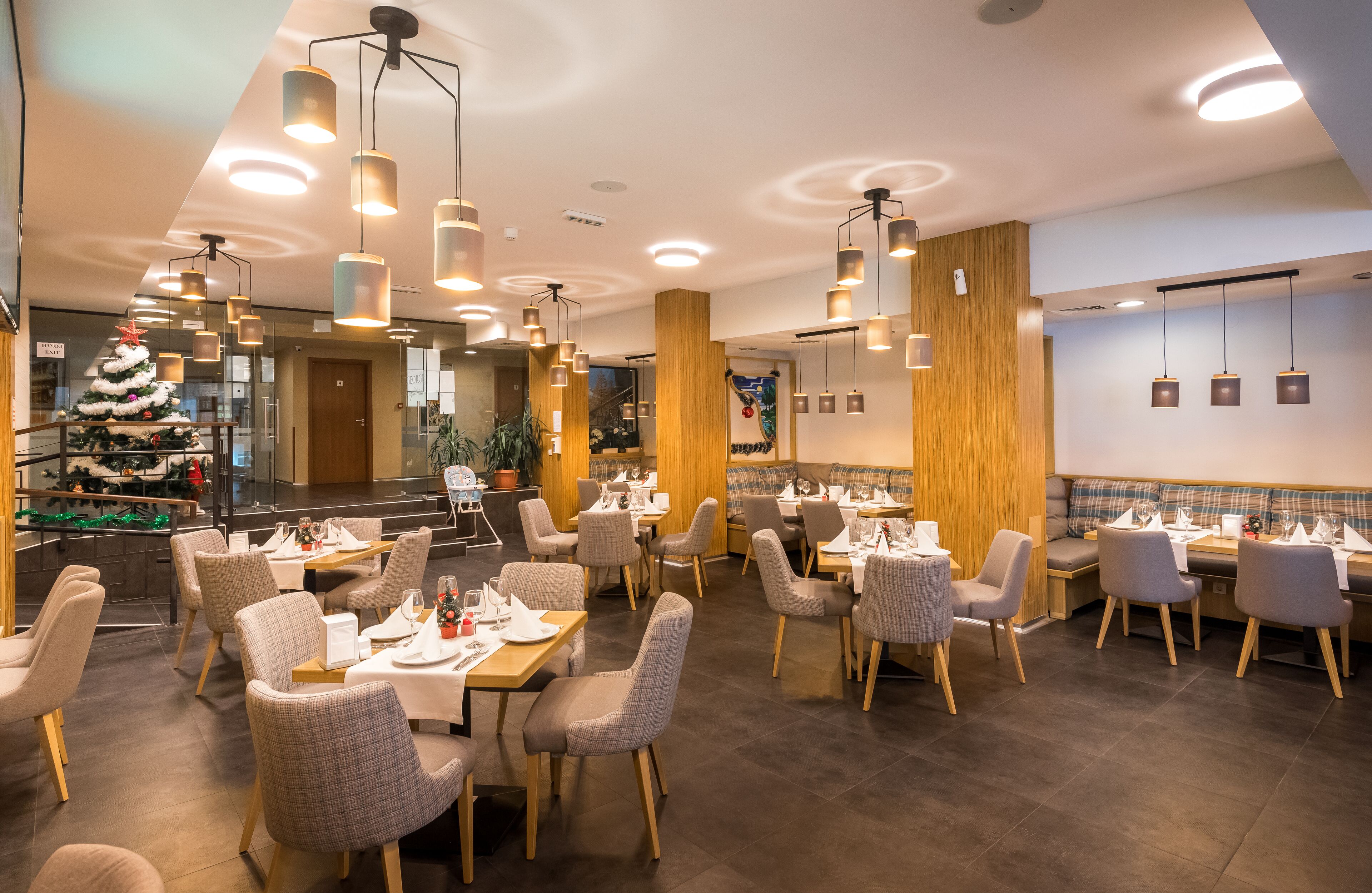 Ein Restaurant mit Weihnachtsbaum, moderner Pendelleuchten und einer Mischung aus Tischen und Sitzecken.