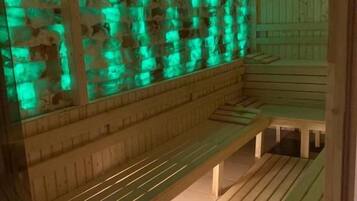 Una sauna de madera con bancos y una pared con iluminación verde.