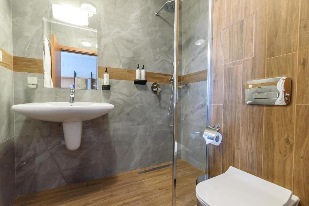 A bathroom with a glass-enclosed shower, a sink with a mirror, and a toilet.