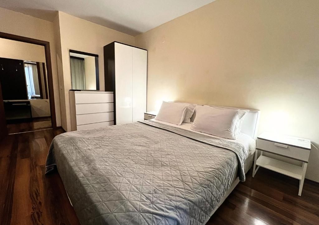 Un dormitorio con cama, cómoda, mesita de noche y espejo.