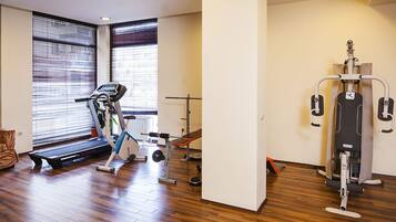 Un gimnasio con cinta de correr, banco de pesas y diversas máquinas de ejercicio.