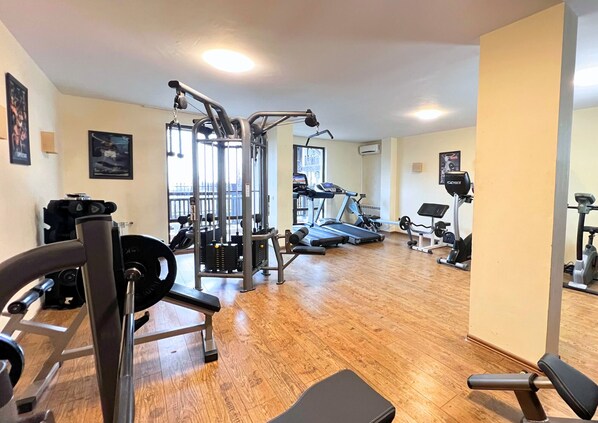 A gym with various exercise equipment, wooden flooring, and a view of the outdoors. - St. George Ski & Holiday (Bansko)