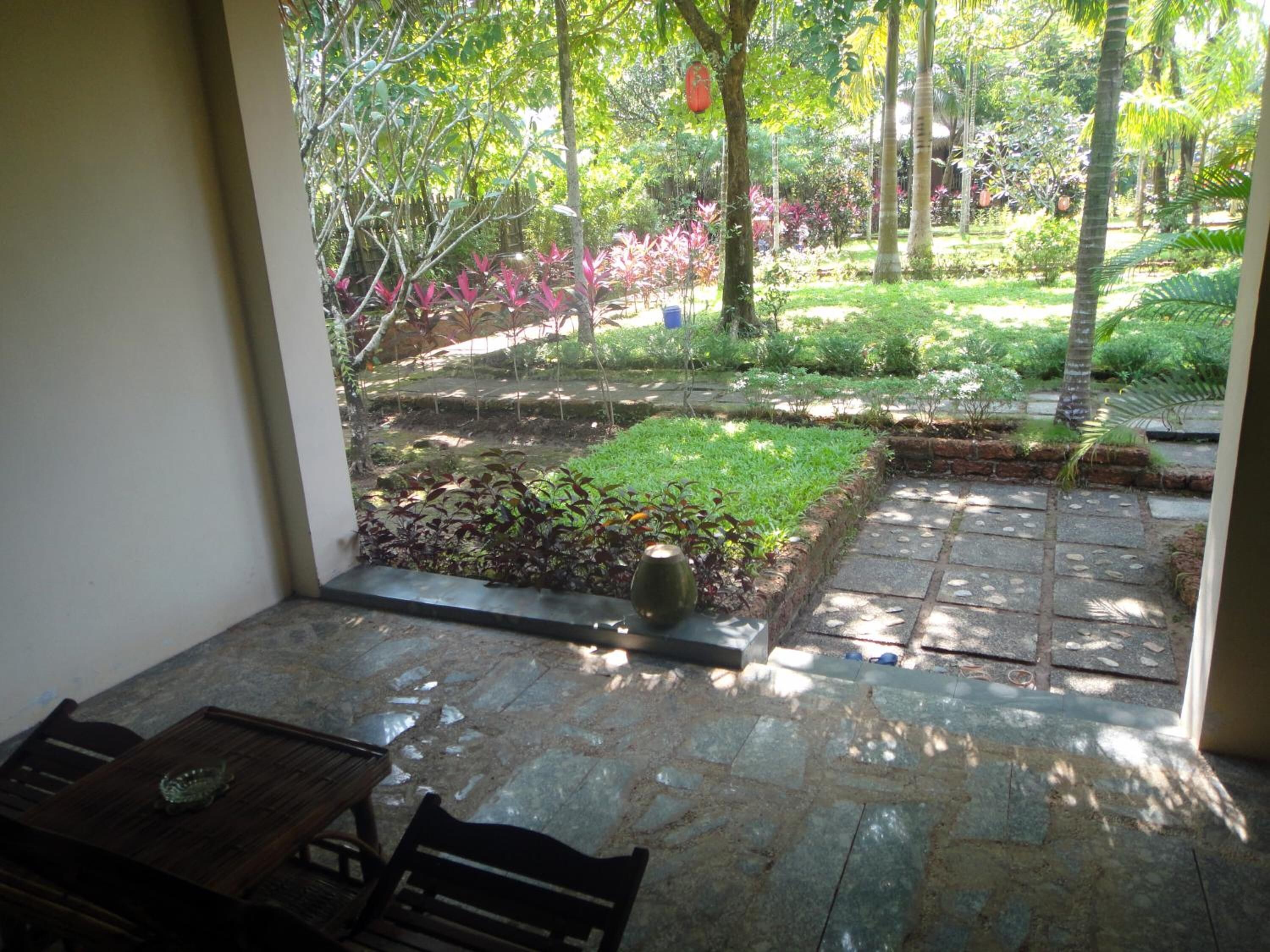 A patio area with stone flooring, a wooden table, and a bench.