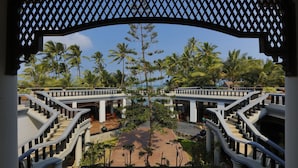 Una escalera simétrica que lleva a una zona de piscina con palmeras y una vista despejada del océano.