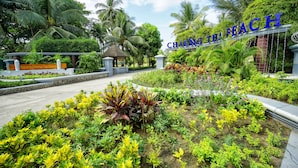 Un exuberante jardín con un pabellón, palmeras y un letrero que dice 'Chau Gai The Resort'.