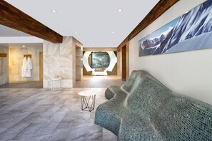 A modern lobby with a large, curved seating area, a small table, and a view of a mountainous landscape through a circular window. - Four Points by Sheraton Bansko (Bansko)