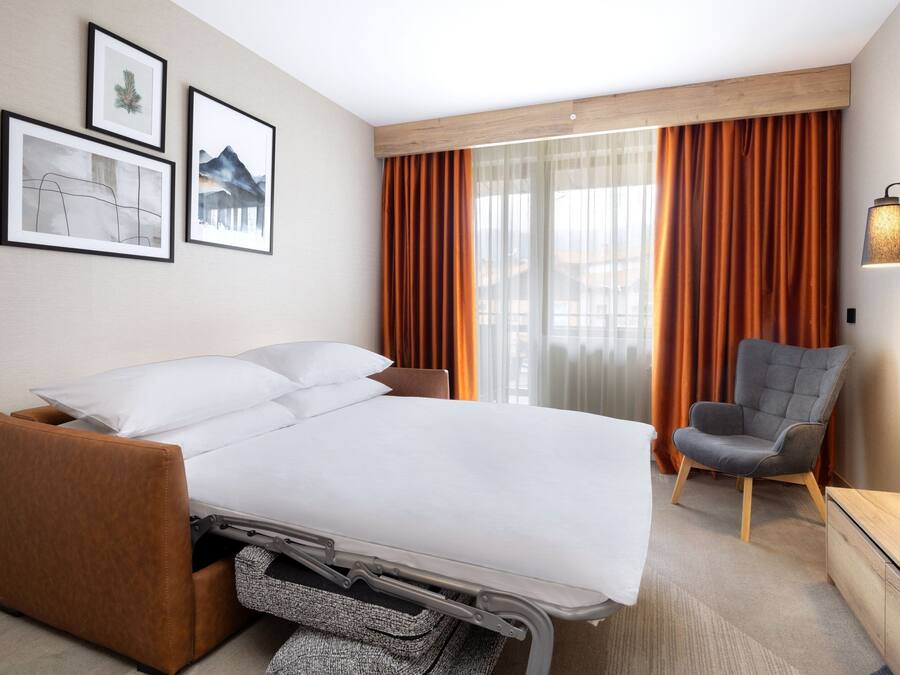 Una habitación de hotel moderna con una cama, una silla y obras de arte en la pared.