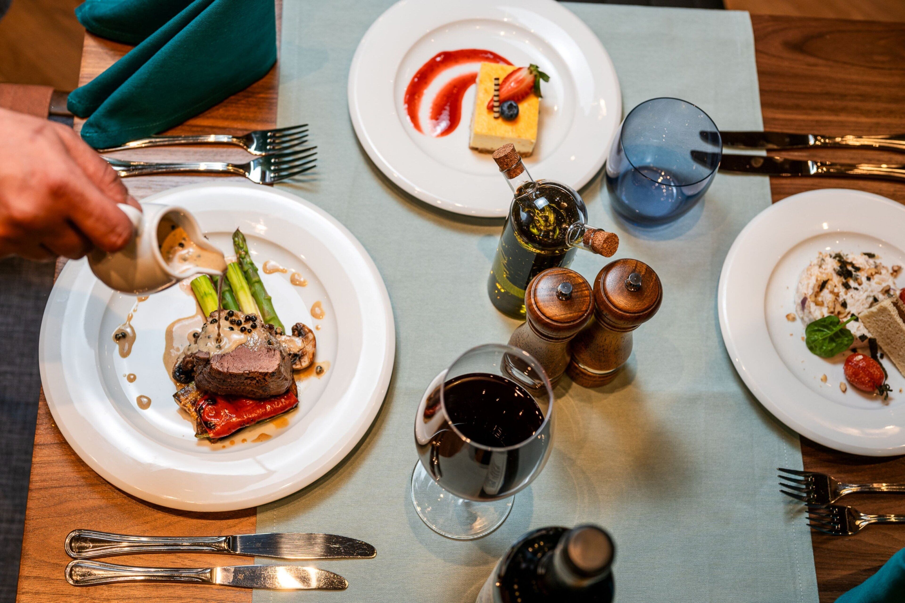 A dining table with plates of food, cutlery, and glasses.