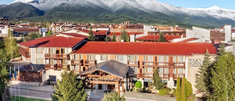 A hotel with a red roof, wooden balconies, and a sign reading "FOUR POINTS BY SHERATON".