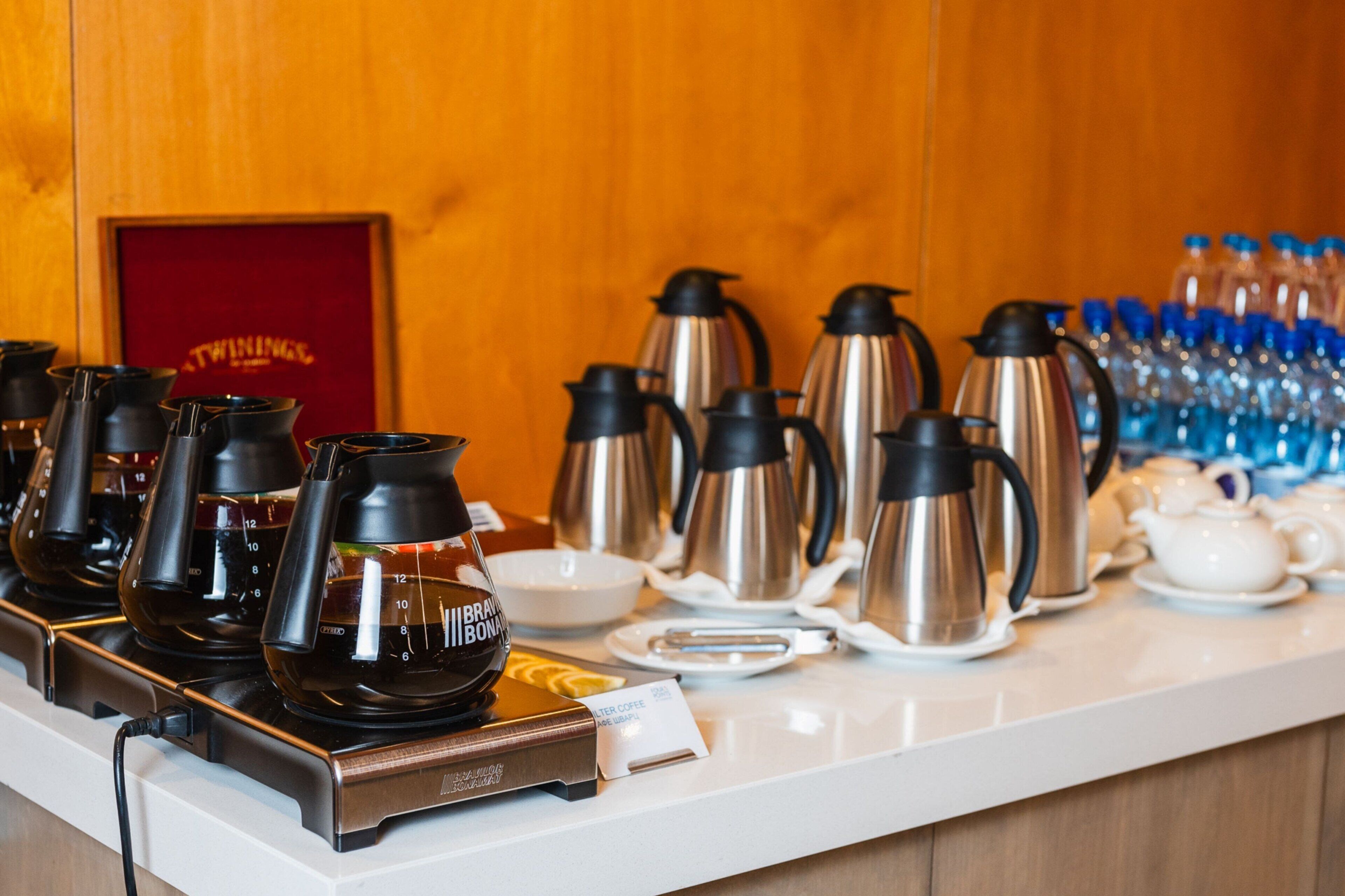 Una estación de café con varias cafeteras y una caja de café con la marca.