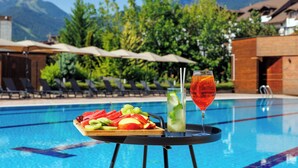 A poolside table with a fruit platter and drinks, surrounded by lounge chairs and a mountain view. - Four Points by Sheraton Bansko (Bansko)