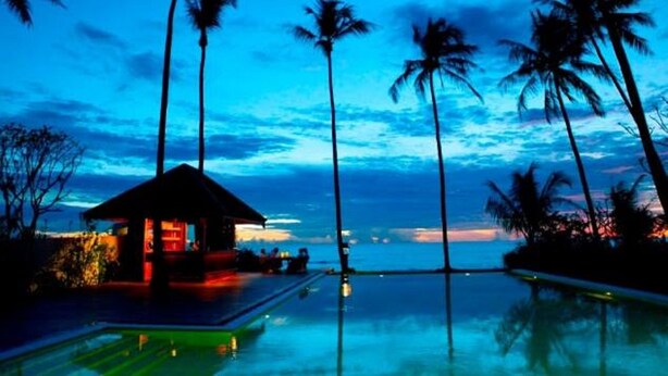 A resort with a pool, palm trees, and a building with lights. - Amara Ocean Resort (Thandwe)