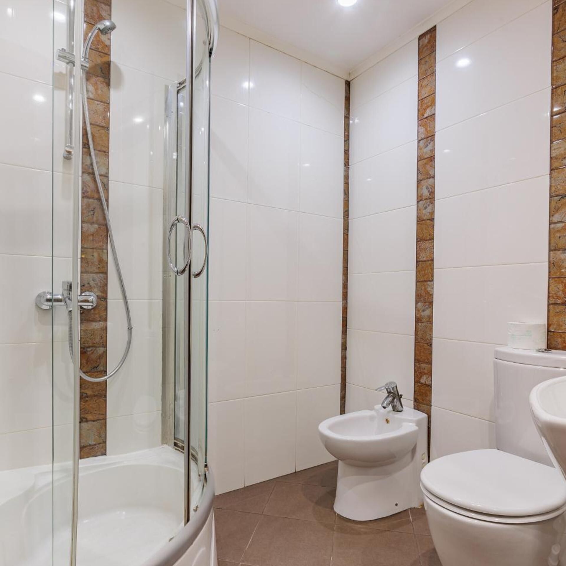 A bathroom with a glass-enclosed shower, a toilet, and a bidet.