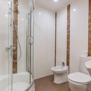 Un baño con ducha envuelta en vidrio, inodoro y bidé.