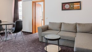 Una sala de estar con un sofá gris, una mesa redonda de centro y un comedor con una mesa y sillas.