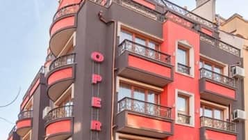 Un edificio de varios pisos con balcones, un cartel que dice 'OPERA' y un letrero que indica 'Hotel'.