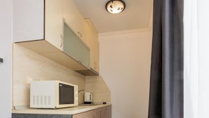 Una cocina compacta equipada con microondas, cafetera y armario.