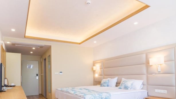A modern hotel room with a large bed, bedside lamps, a wooden desk, and a built-in wardrobe. - Bilyana Beach (Nesebar)